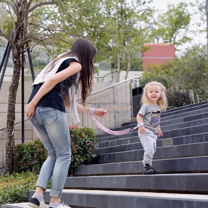 Toddler and parent walking down stairs connected by a pink child anti-lost wrist strap