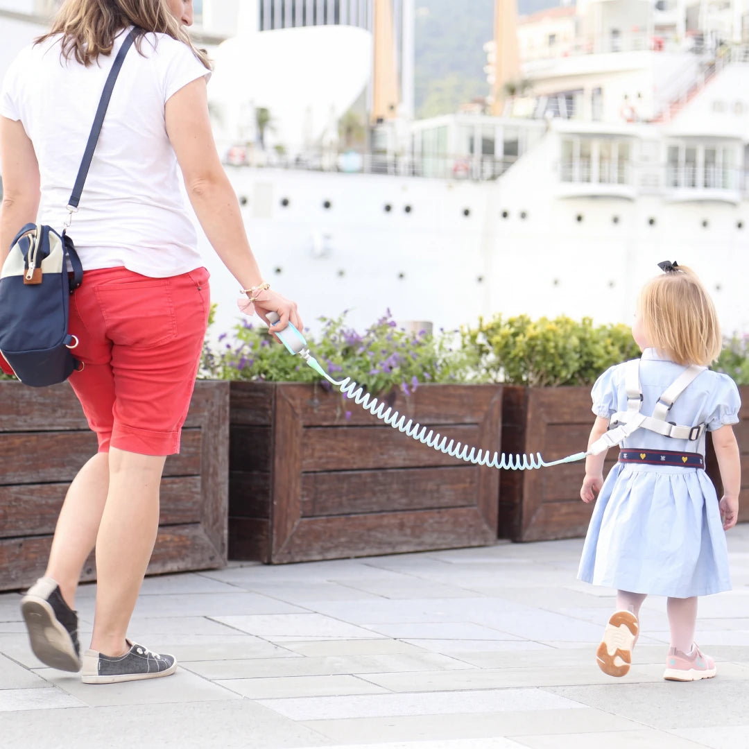 Pink child safety harness with coiled leash, flat view