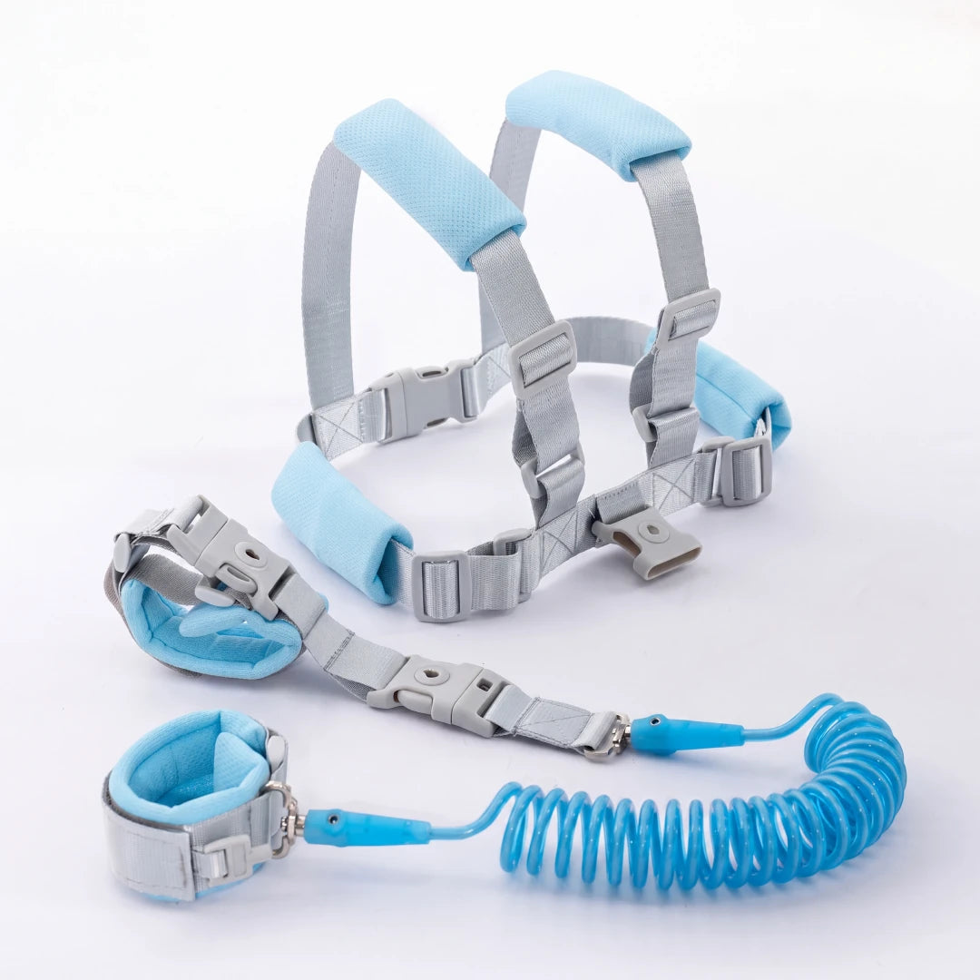 Toddler walking outdoors wearing the blue child safety harness with parent holding the leash